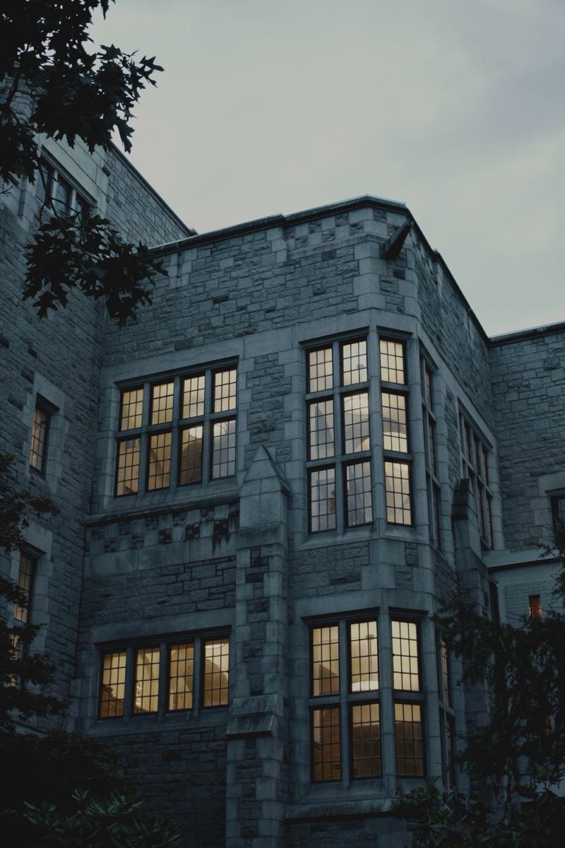 Dusk photograph of a stone UBC building with warmly lit windows